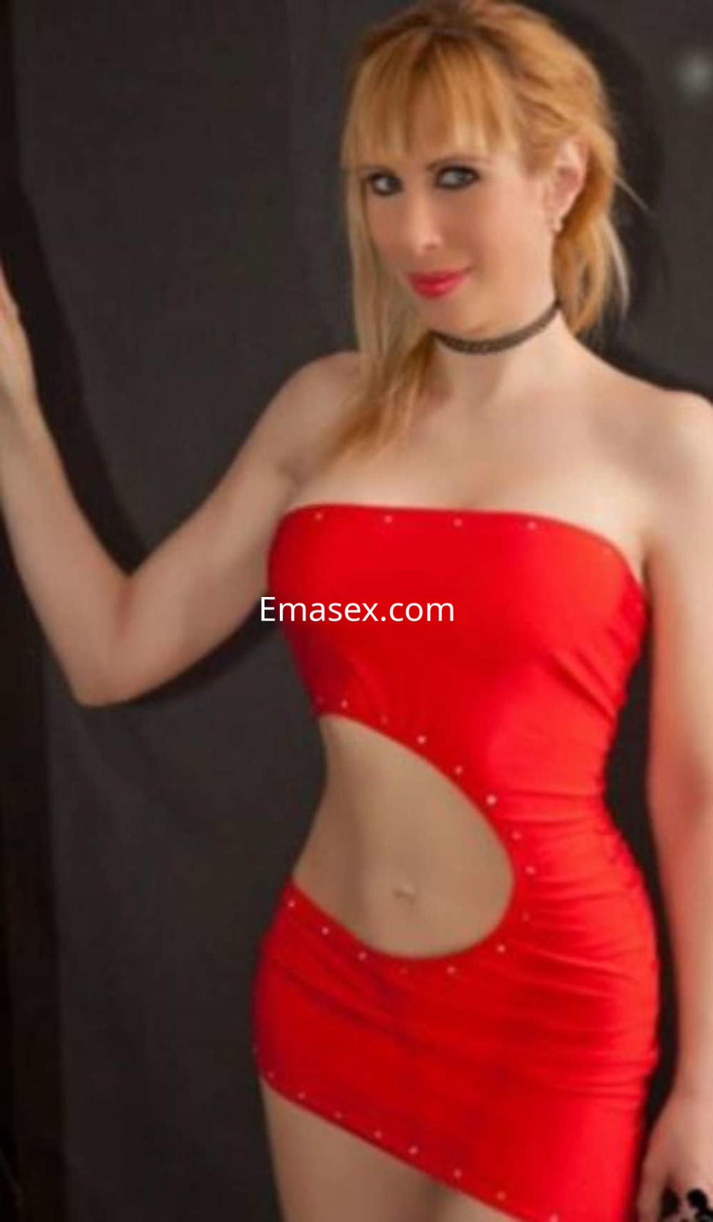 Escort en Valencia luciendo un vestido rojo ajustado con detalles en el cuello y una pose coqueta.