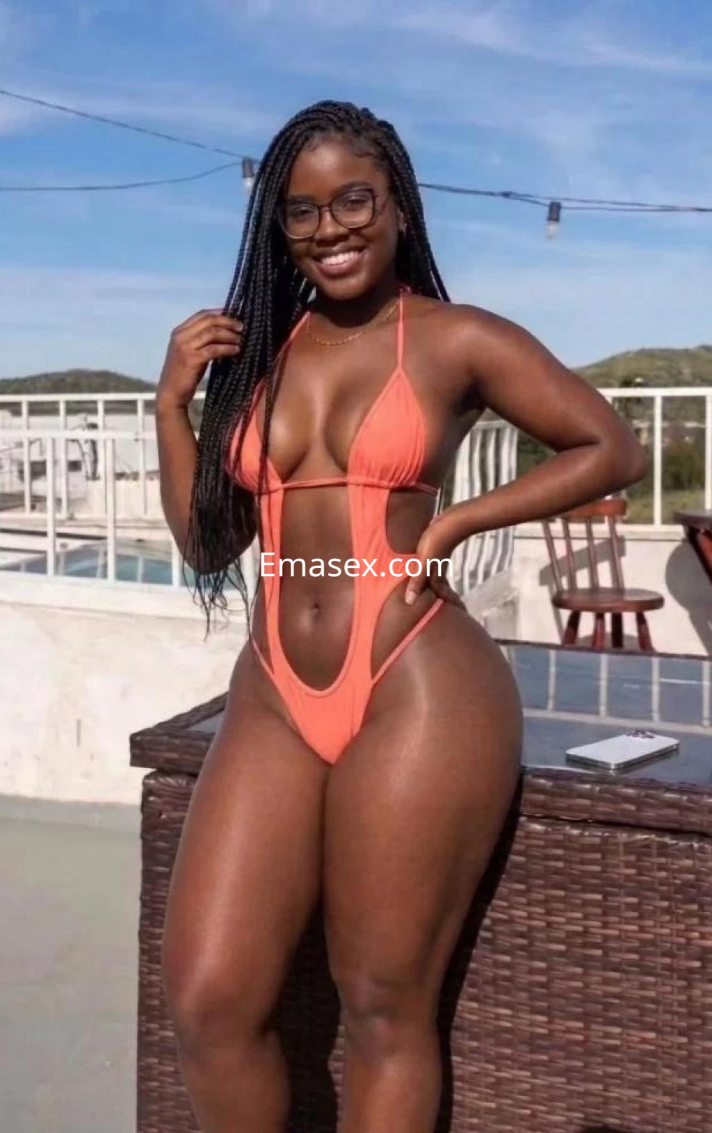 Puta posando junto a una piscina en Coruña, lleva un bañador de color naranja y gafas, mostrando confianza.