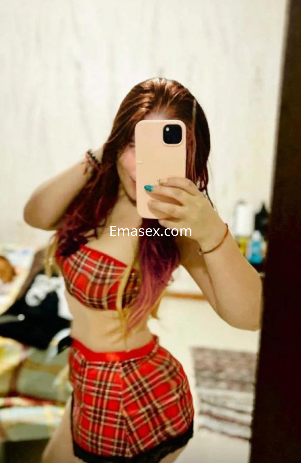 Escort en Coruña posando con un conjunto de lencería de cuadros rojos y amarillos, con cabello largo y ondulado.