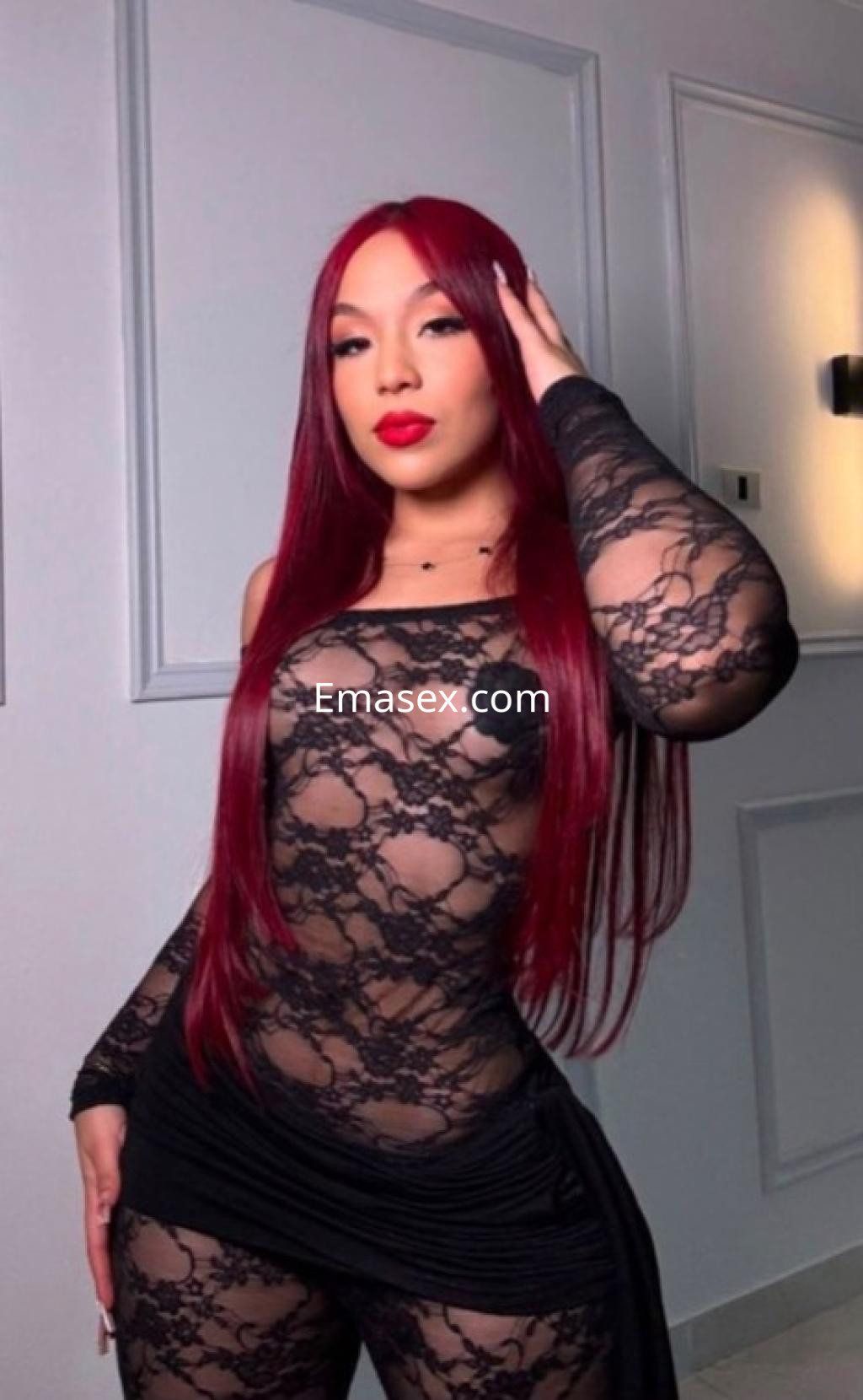 Escort en Coruña luciendo un conjunto de lencería negra con detalles de encaje y cabello largo y rojo.