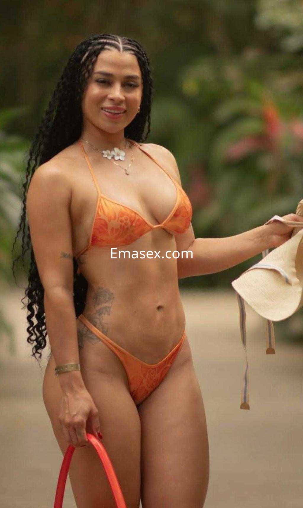Puta con cabello largo y rizado, vistiendo un bikini naranja, sonríe en un entorno natural en Vigo.
