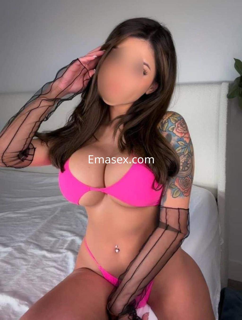 Escort en Ibiza posando con un sujetador rosa y lencería a juego, complementada con guantes negros de encaje.