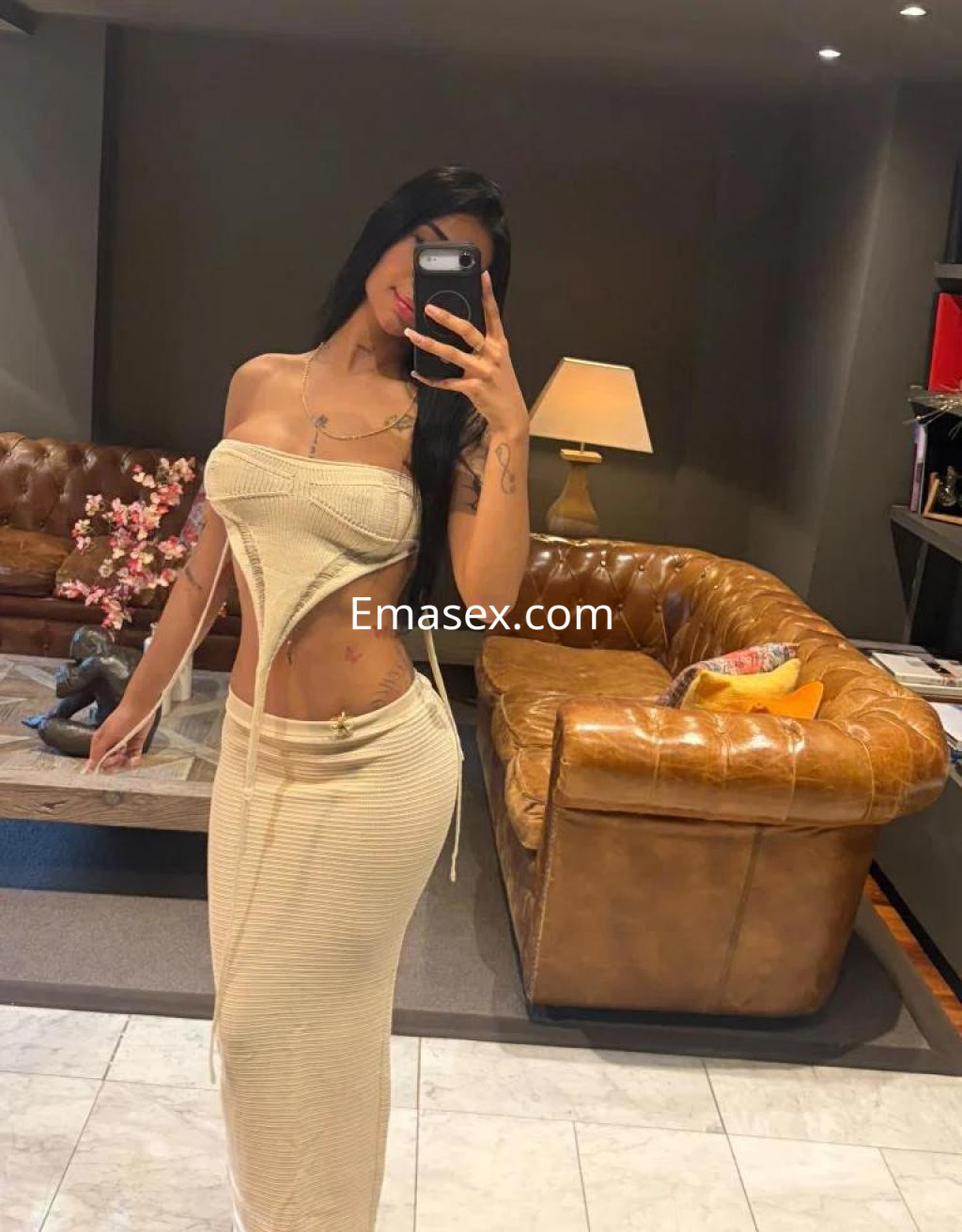 Escort en Barcelona posando con un vestido ajustado y abierto en el costado, con cabello largo y oscuro.