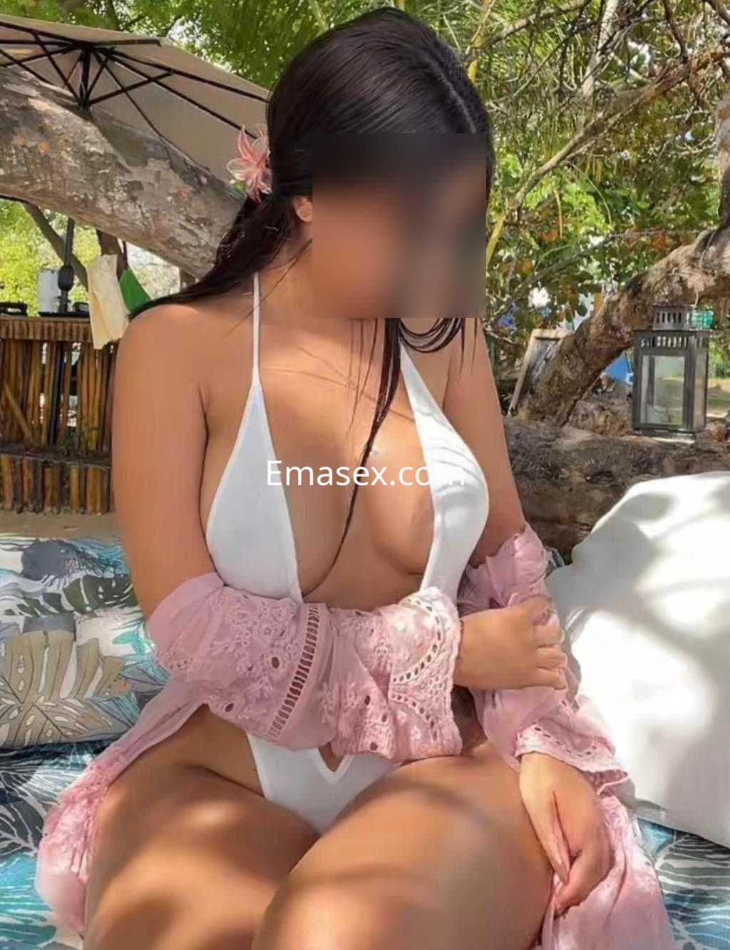 Escort en Tarragona, vistiendo un bikini blanco y una chaqueta rosa, posando en un entorno natural y soleado.