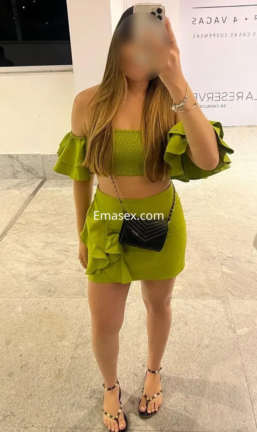Puta en Valencia, luciendo un conjunto verde con volantes y una falda corta, posando frente a un espejo.