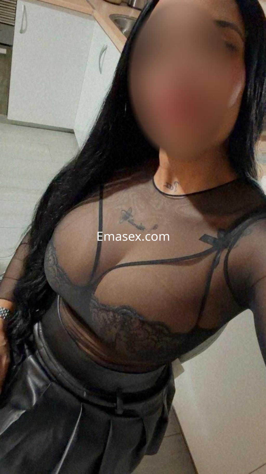 La puta se retrata en una cocina, vistiendo una blusa transparente con encaje y una falda de cuero en Valladolid.