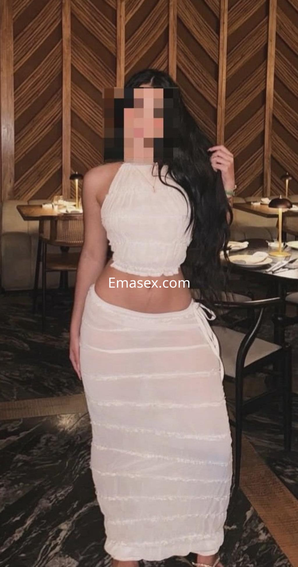 Puta en Valladolid luciendo un vestido blanco ajustado que resalta su figura en un elegante restaurante.