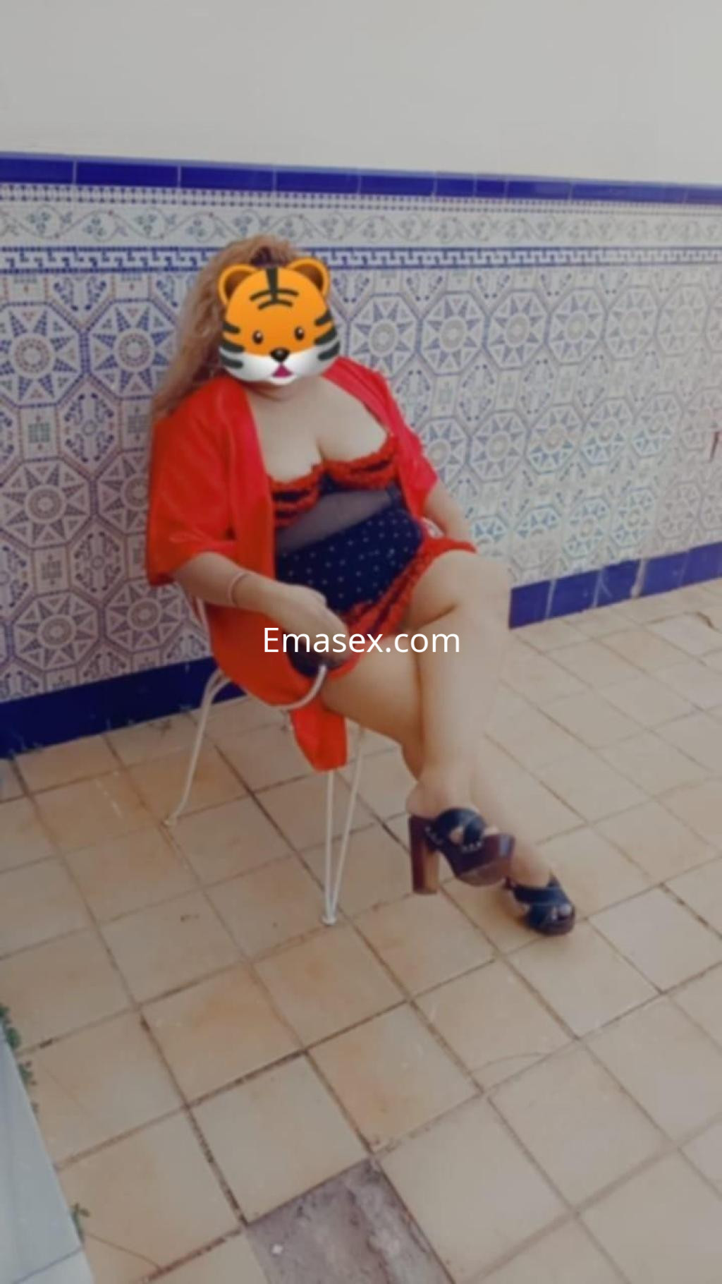 Puta sentada en una silla con lencería negra y un kimono rojo, en un ambiente exterior de Almería.