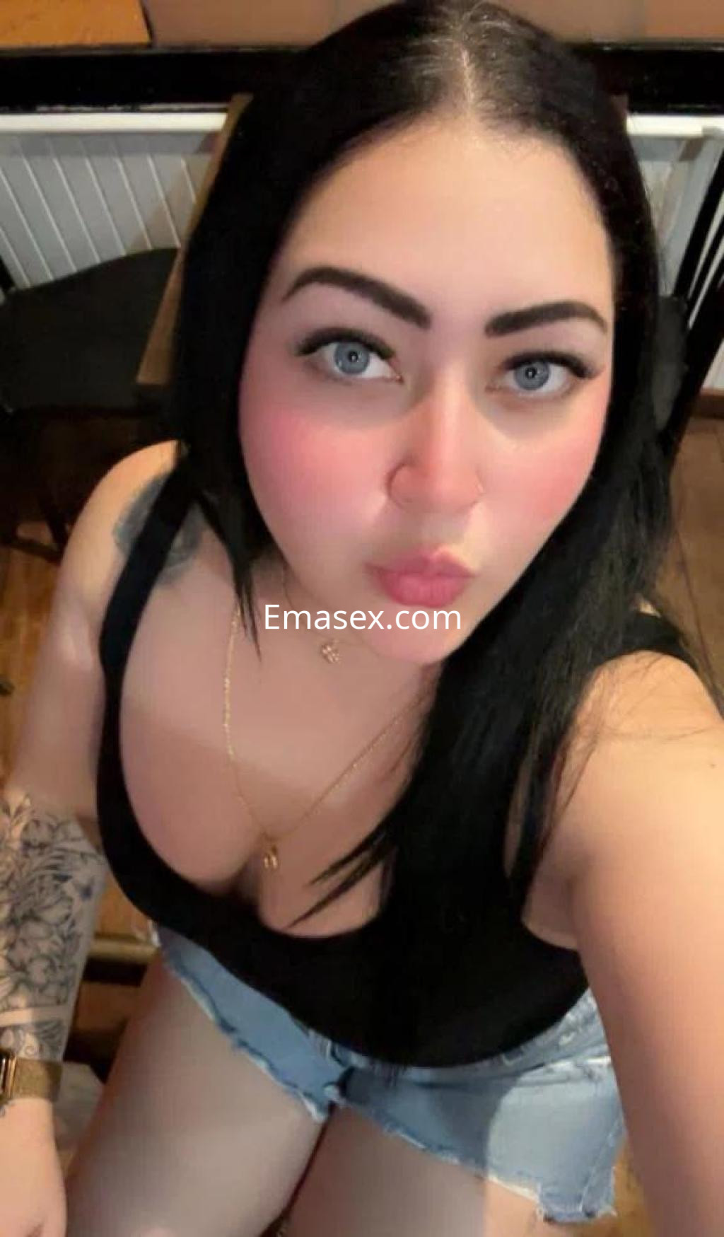 Escort en Palma de Mallorca con cabello largo y oscuro, luciendo un top negro y shorts de mezclilla.