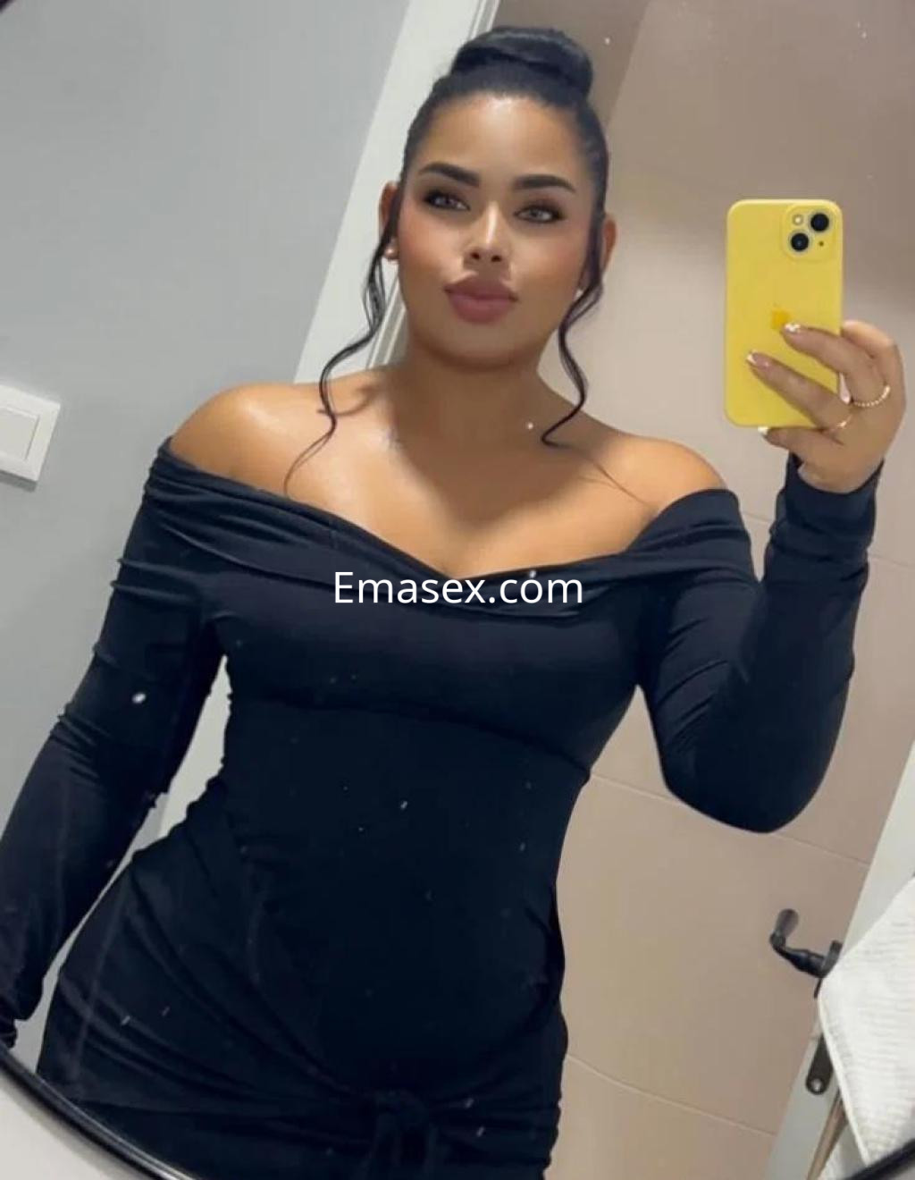 La puta en Cádiz se muestra en un vestido negro ajustado, con un escote pronunciado y cabello recogido.