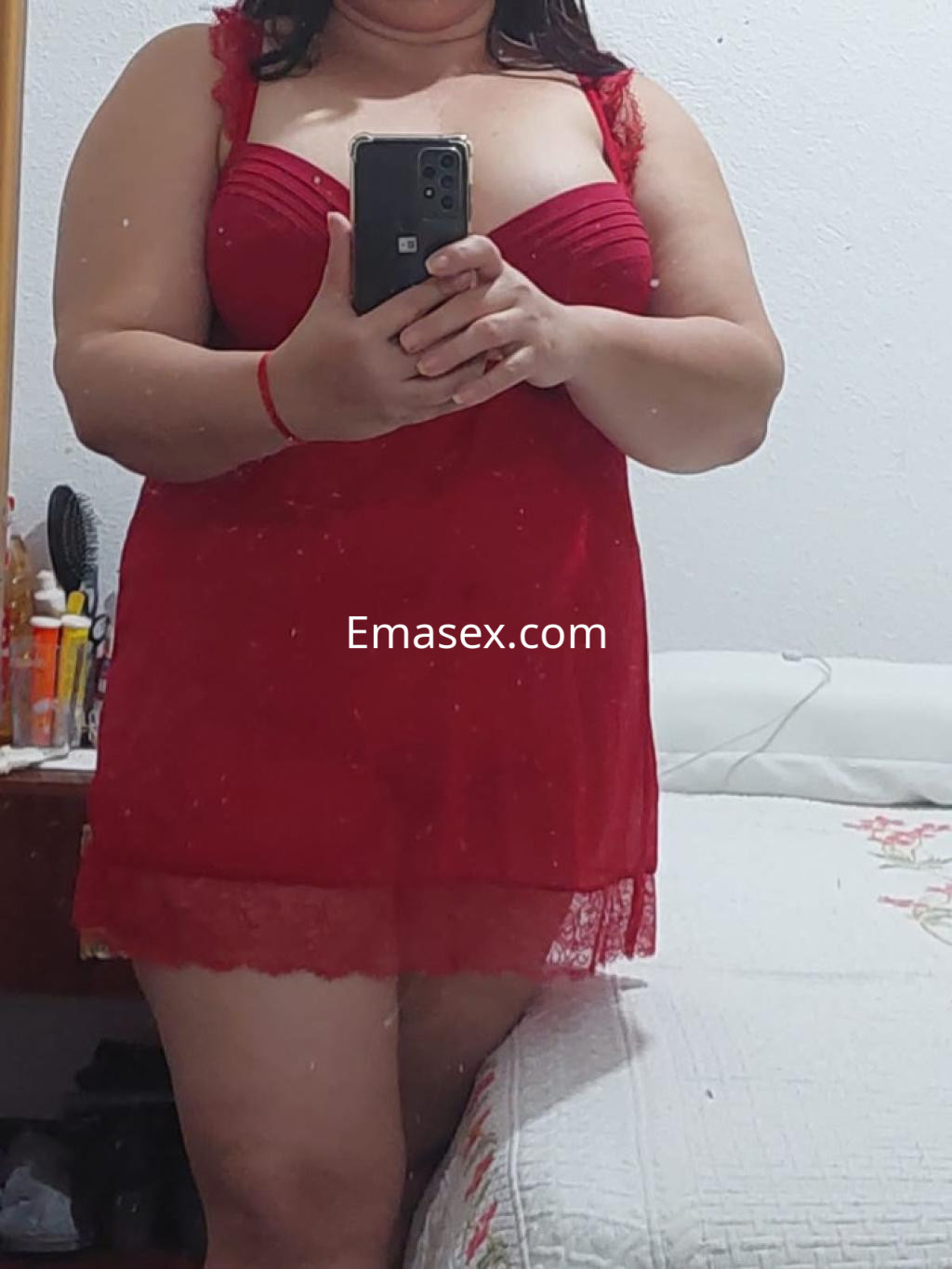 Escort en Lugo, con un vestido rojo de encaje que destaca su figura, posando frente al espejo.
