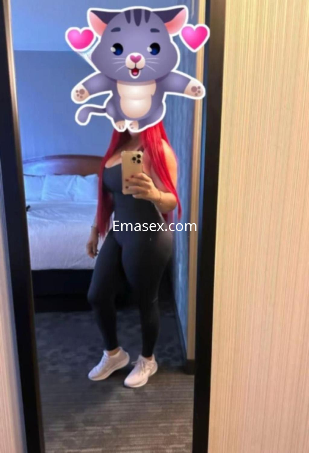 Escort en Pontevedra con cabello largo y rojizo, vestida con un conjunto ajustado y zapatillas deportivas en un espejo.