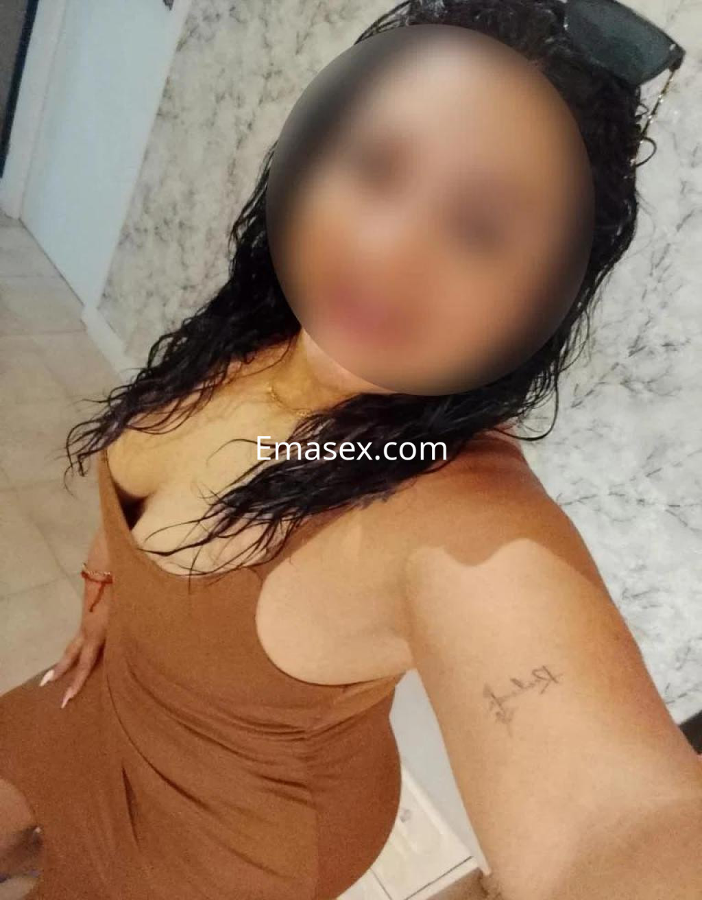 Puta posando en Tenerife con un vestido marrón ajustado, con el cabello rizado y un entorno interior.
