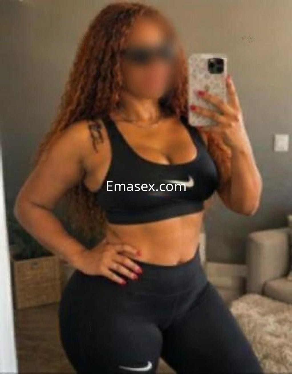 La puta luce un conjunto deportivo negro, con cabello rizado y de color castaño, en un ambiente interior en Tenerife.