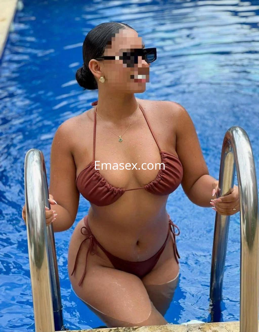 Escort en Tarragona posando junto a una piscina, con un bikini marrón y gafas de sol, mostrando una actitud relajada.