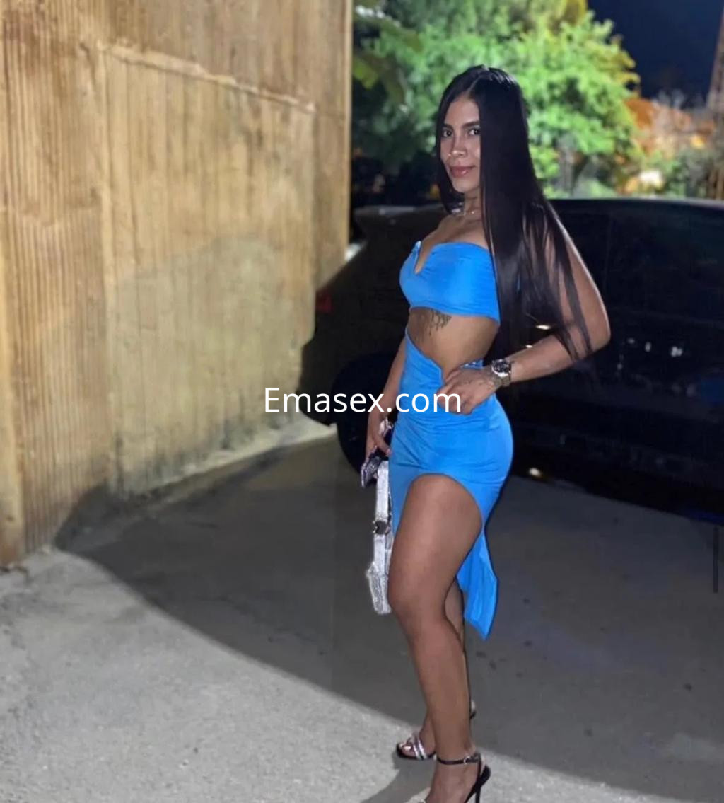 Puta posando en Valencia con un vestido azul ajustado, cabello largo y lacio, mostrando una pierna.