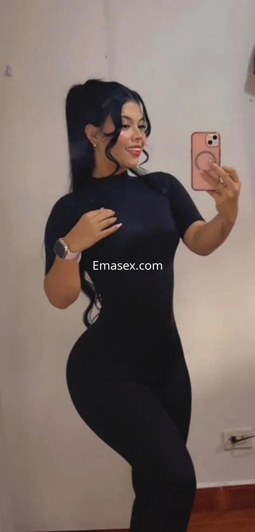 La puta se toma una selfie en Alicante, vistiendo un atuendo negro ajustado que resalta su figura curvilínea.