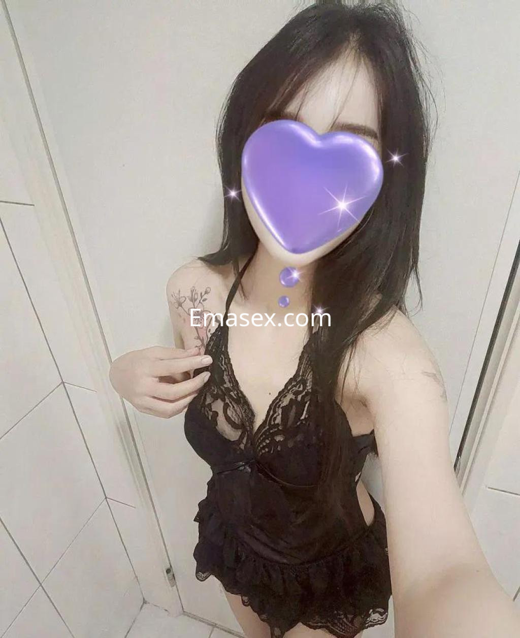 Escort en Barcelona con cabello largo y oscuro, usando un conjunto de lencería negra con encaje en un entorno interior.
