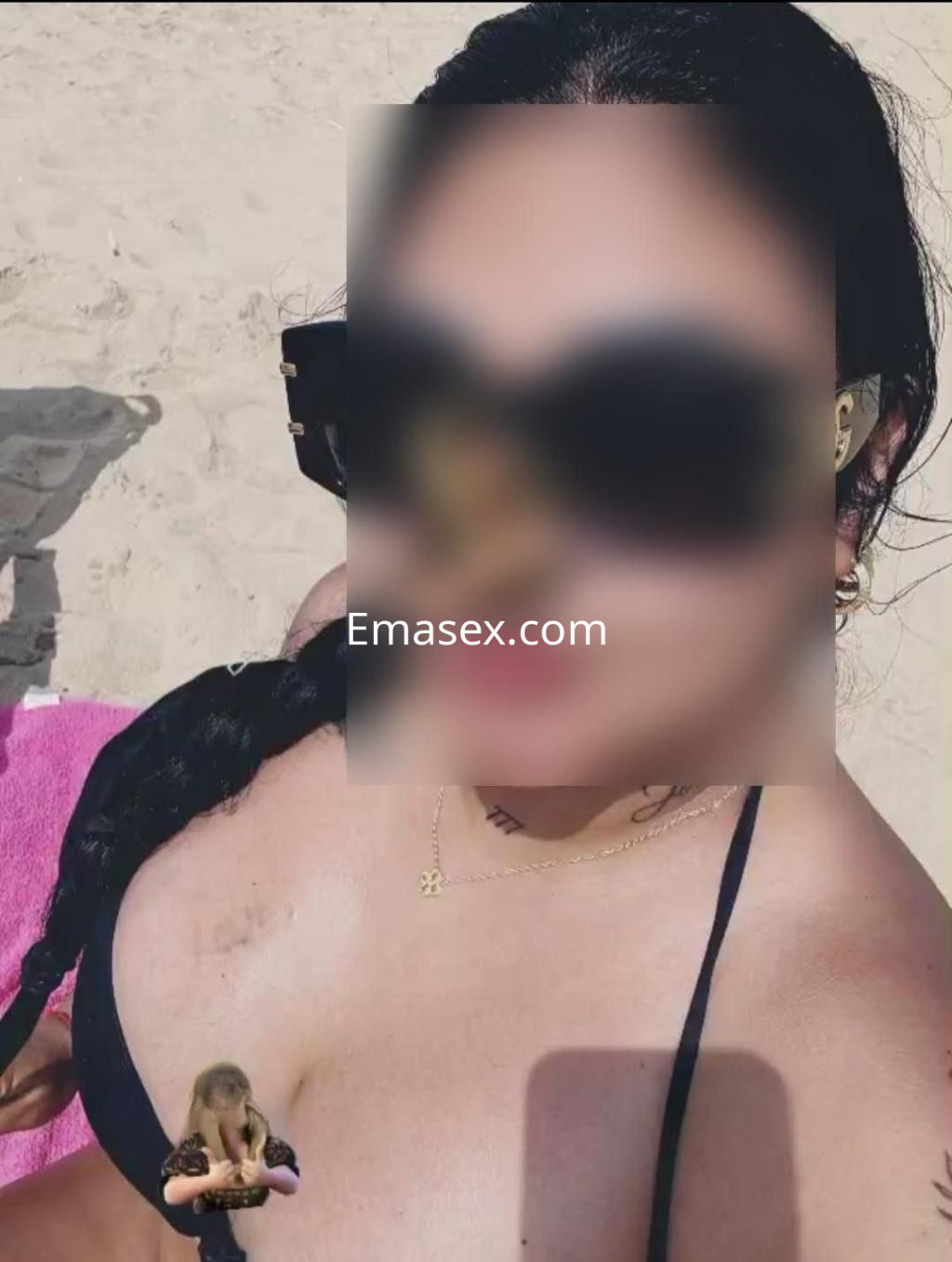 Puta con cabello oscuro y trenzado, usando un bikini negro, descansando en la playa de Huelva.