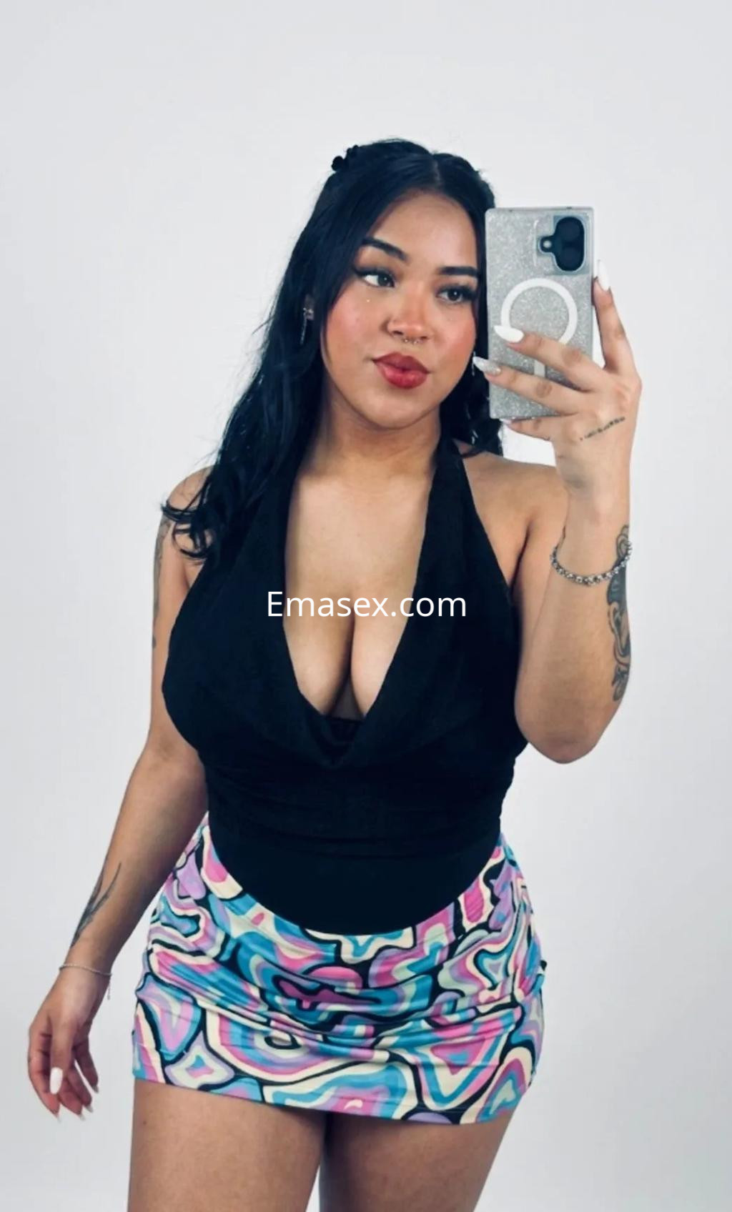 Escort de piel clara con cabello oscuro y ondulado, luciendo un top negro y una falda colorida, posando en Málaga.