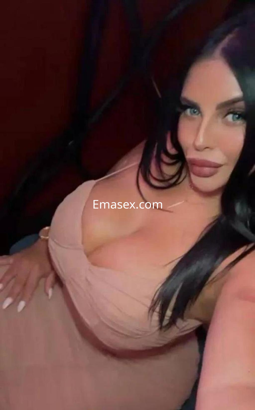 Escort en Málaga con cabello largo y oscuro, luciendo un vestido ajustado de color nude en un entorno acogedor.