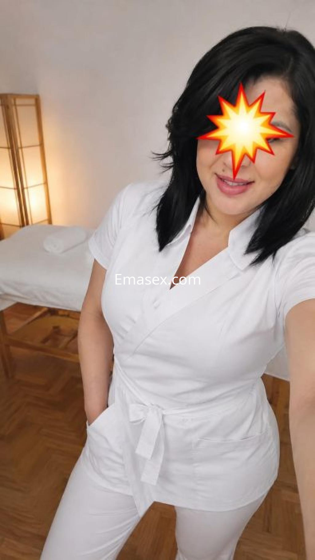 Puta en Pamplona con cabello oscuro, vistiendo un uniforme blanco, sonriendo frente a la cámara.
