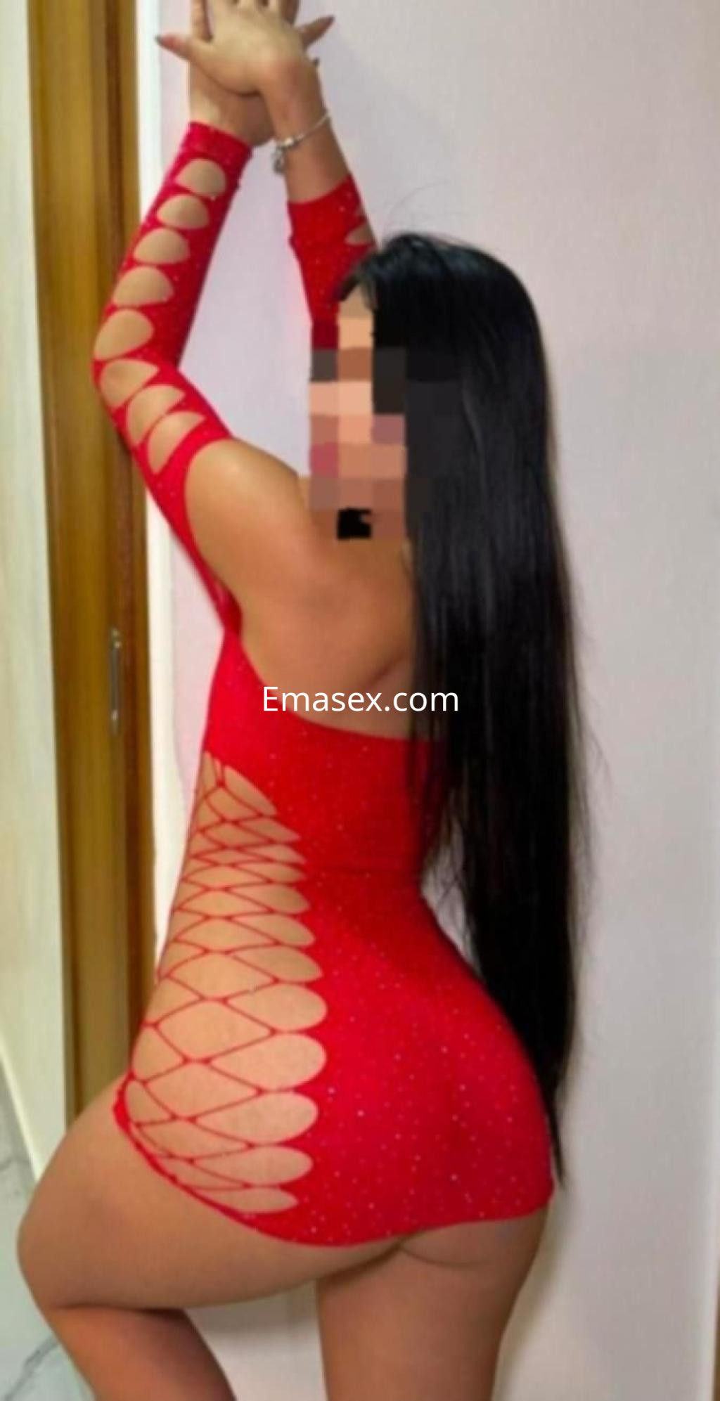 Puta en Valencia con un vestido rojo ajustado y detalles de rejilla, posando de perfil y mostrando su figura.