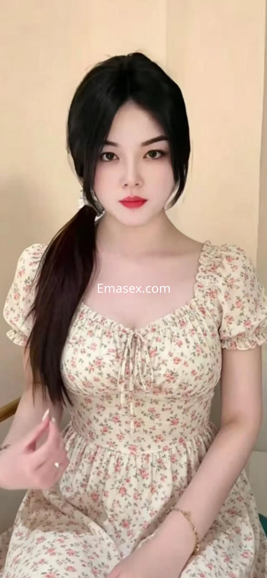 Escort en Alicante con cabello oscuro y lacio, luciendo un vestido de flores con mangas cortas y un fondo neutro.
