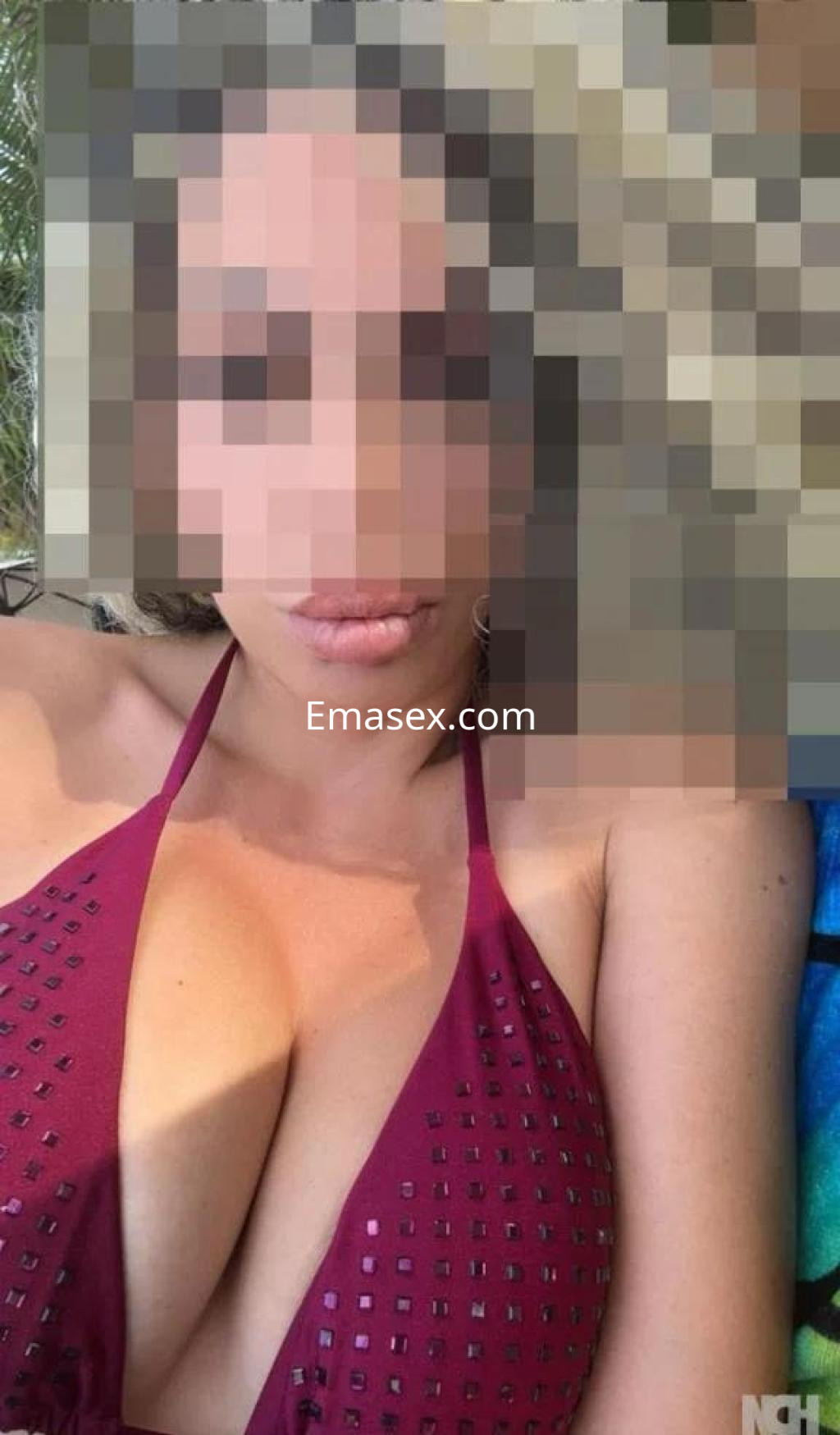 Escort en Barcelona con cabello oscuro, usando un bikini burdeos, posando frente a una superficie de agua.