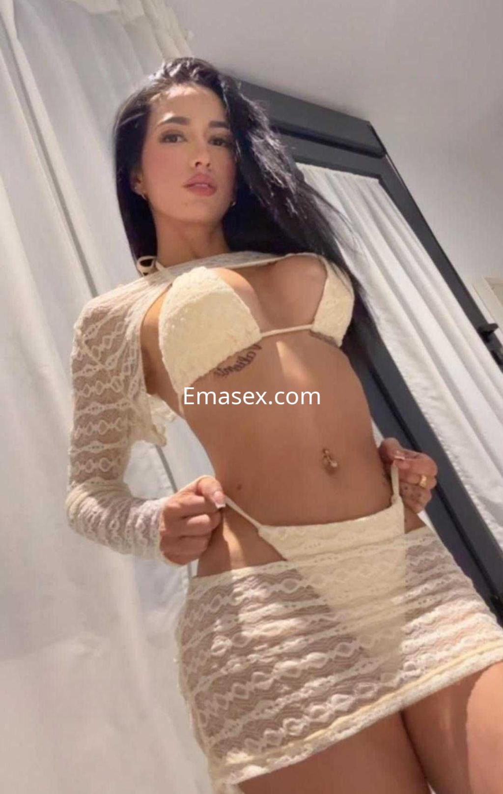 La puta luce un conjunto de lencería blanca y una prenda de encaje en Cádiz, mostrando una pose seductora.