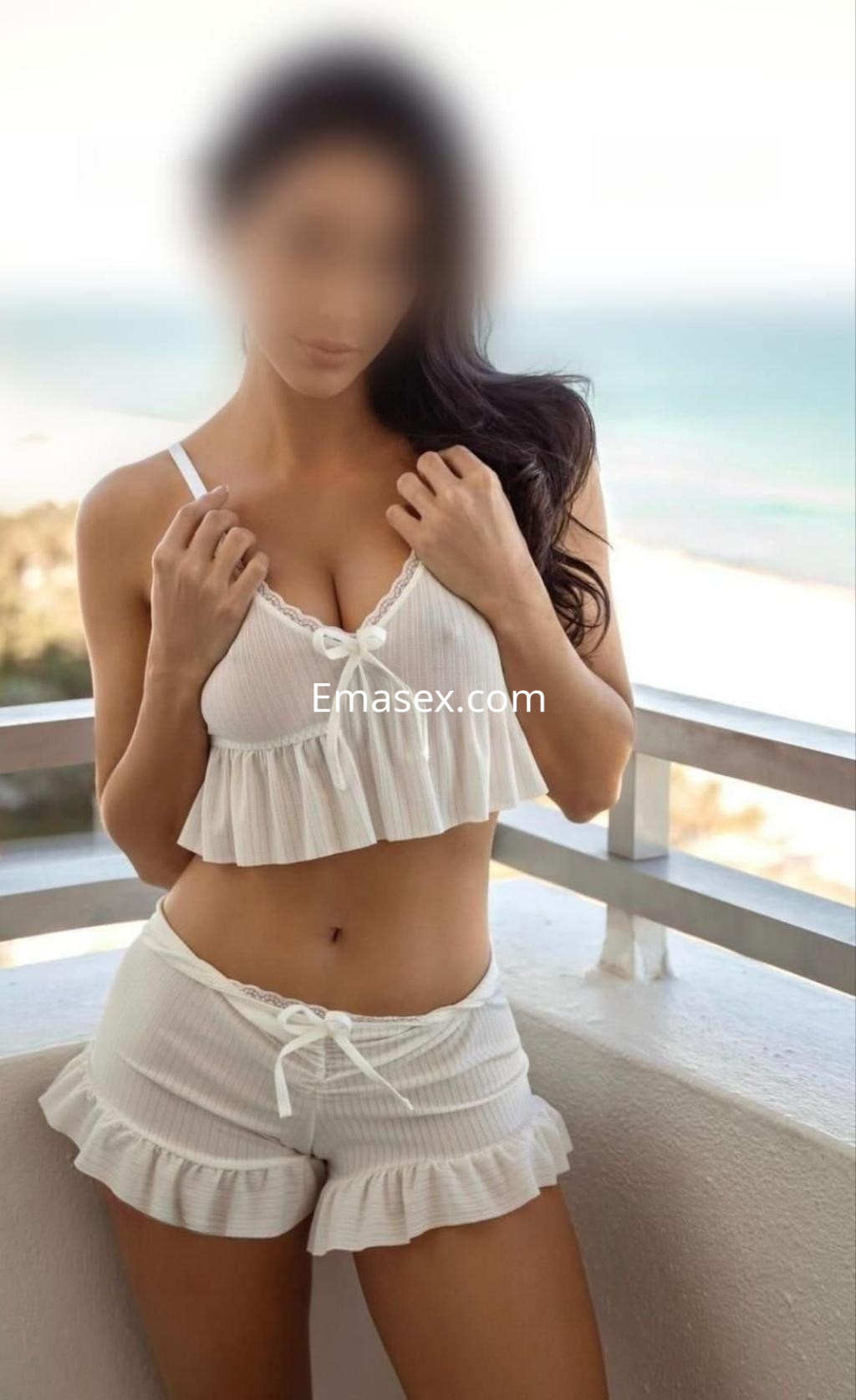 Puta posando en Cádiz con un conjunto de lencería blanco, mostrando una silueta esbelta frente al mar.
