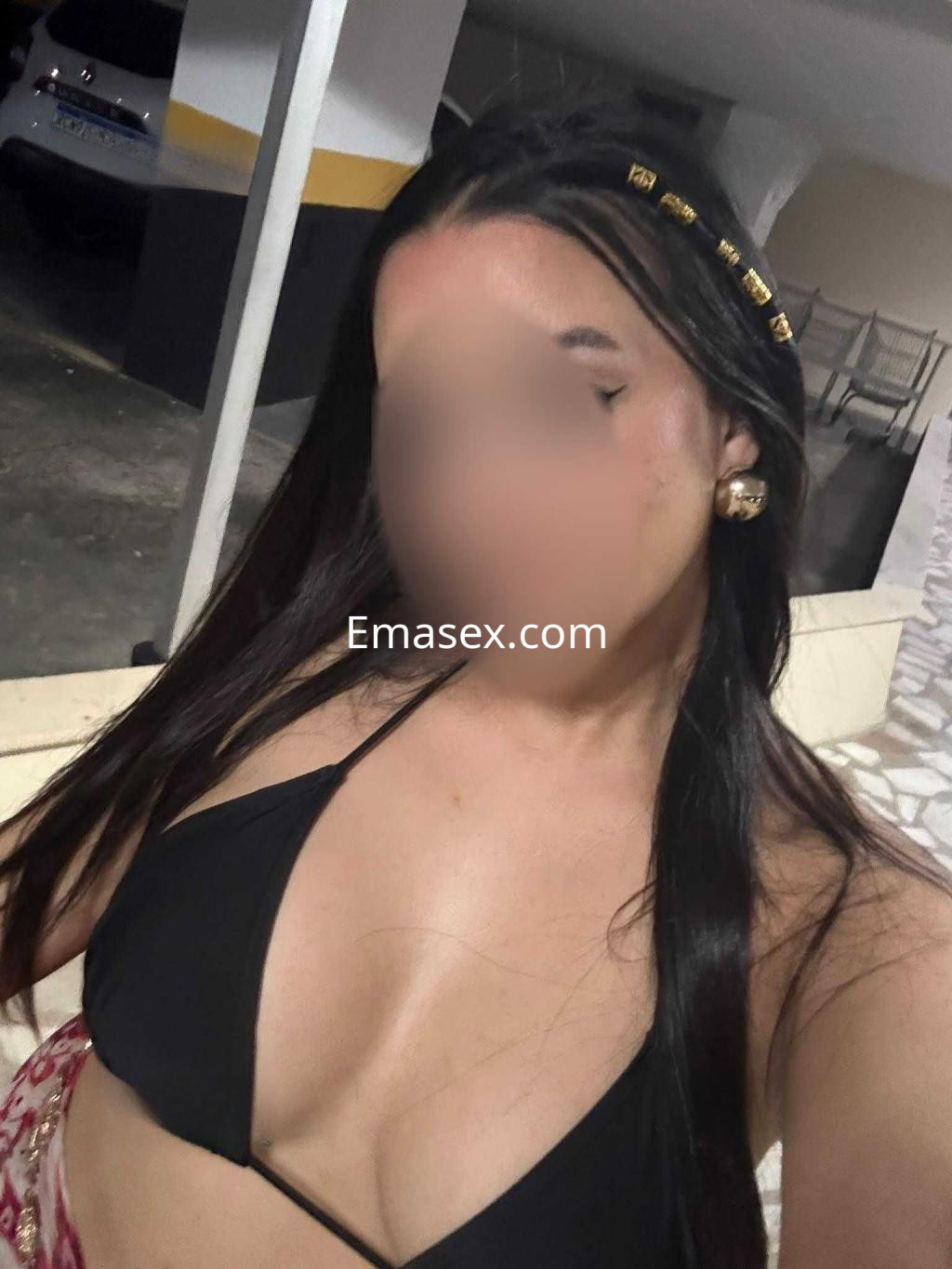Escort en León con cabello largo y lacio, luciendo un top negro y una falda colorida, en un entorno al aire libre.
