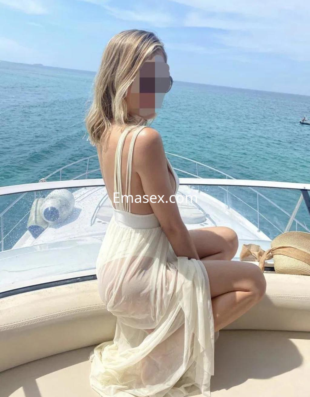 Puta sentada en un yate, luciendo un vestido blanco transparente y disfrutando de una vista al mar en Lugo.
