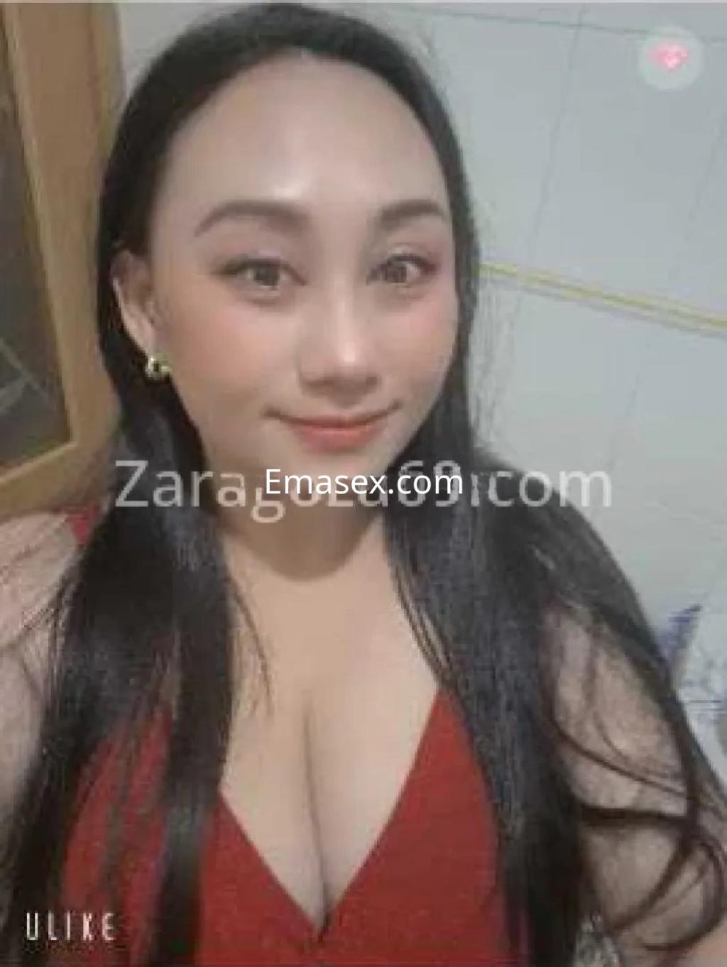 Escort en Zaragoza con cabello largo y lacio, luciendo un vestido rojo y posando sonriente.