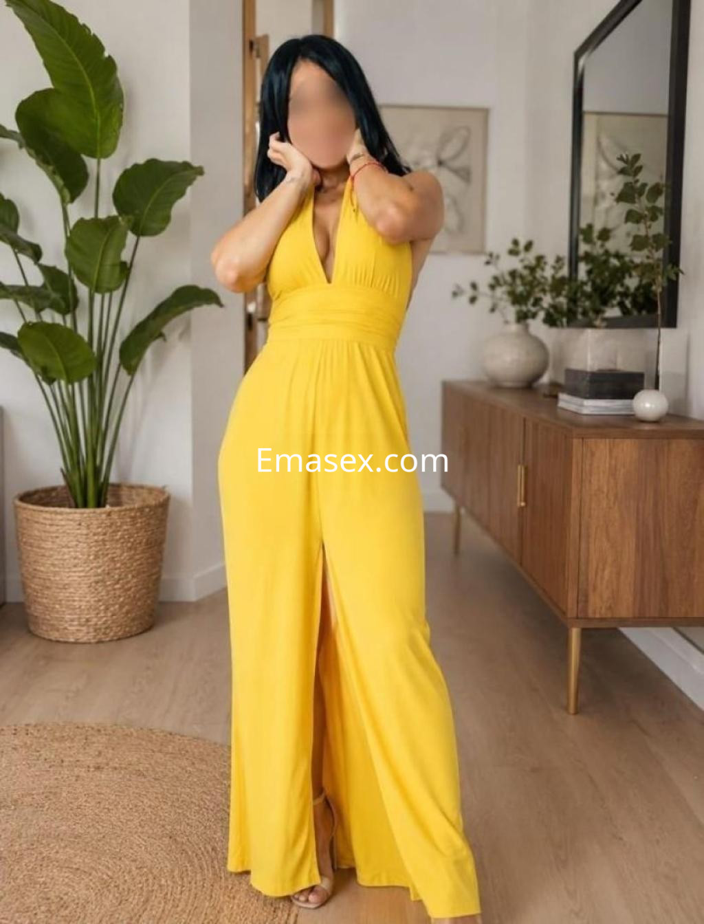 Escort en Zaragoza vistiendo un elegante vestido amarillo con escote, posando en un ambiente acogedor.
