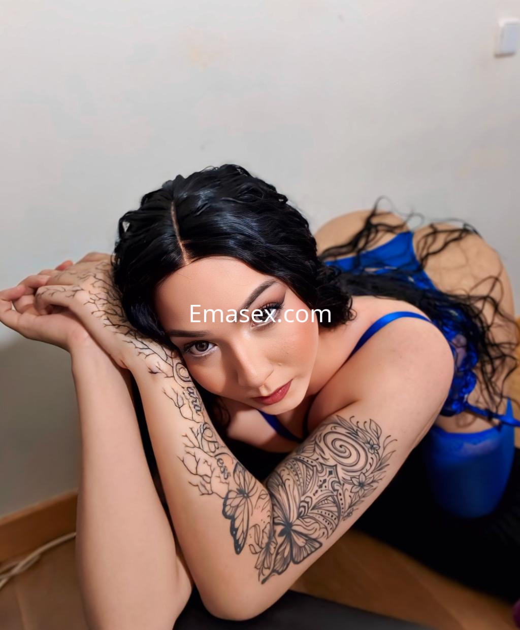 Escort trans en Pamplona, con cabello largo y ondulado, vistiendo un top azul mientras posa con los brazos cruzados.
