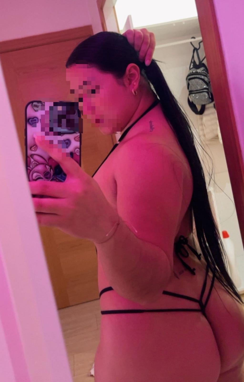 Puta en Vitoria con cabello largo y lacio, vistiendo un bikini negro, posando en un baño con luz tenue.