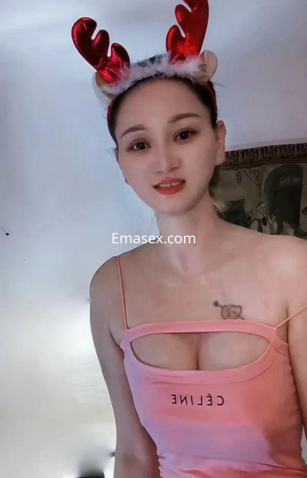 La puta de Palma de Mallorca lleva un top rosa ajustado y una diadema de reno, mostrando un tatuaje en su pecho.