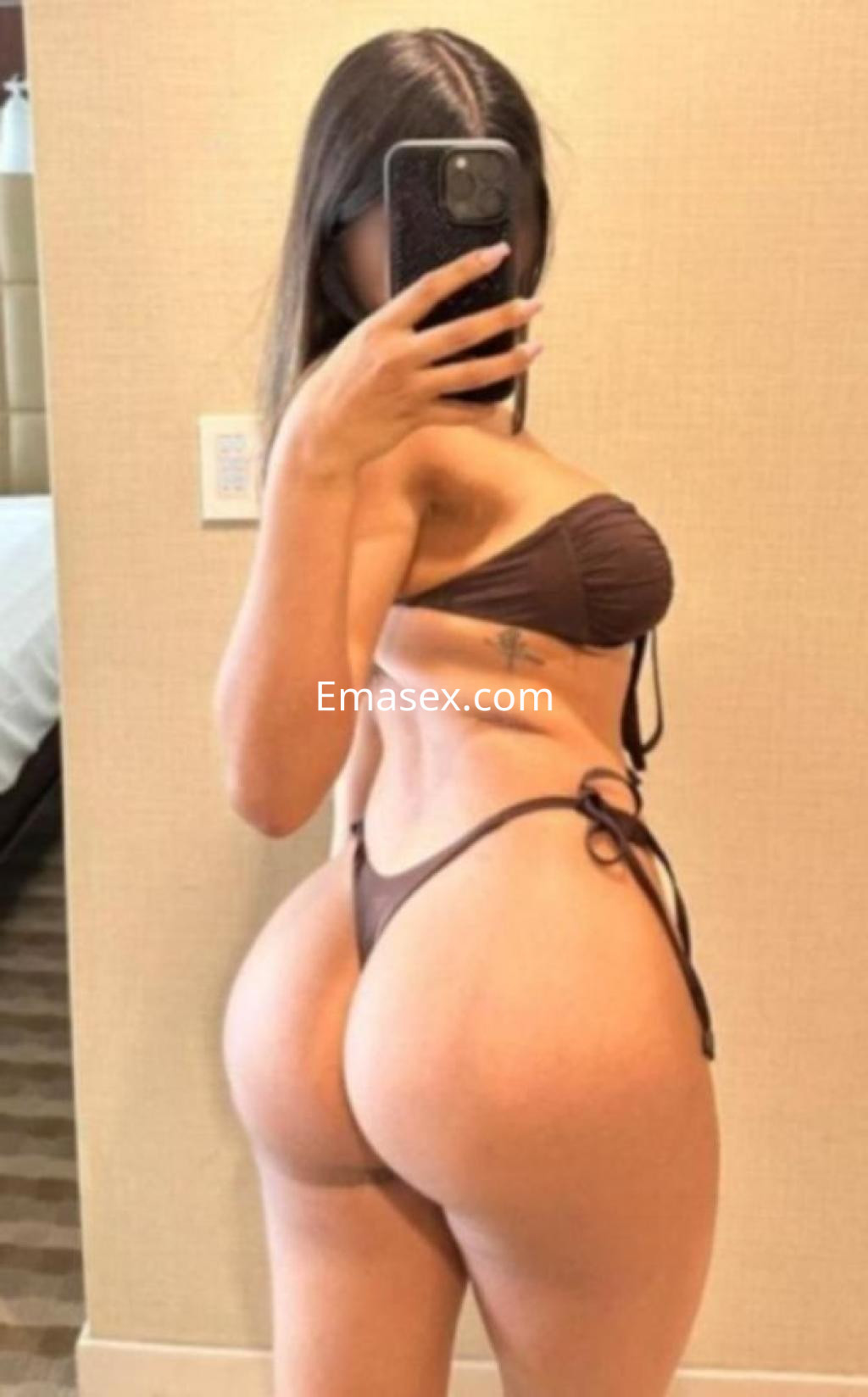 Puta posando de perfil con un bikini marrón en un ambiente interior de Sevilla.