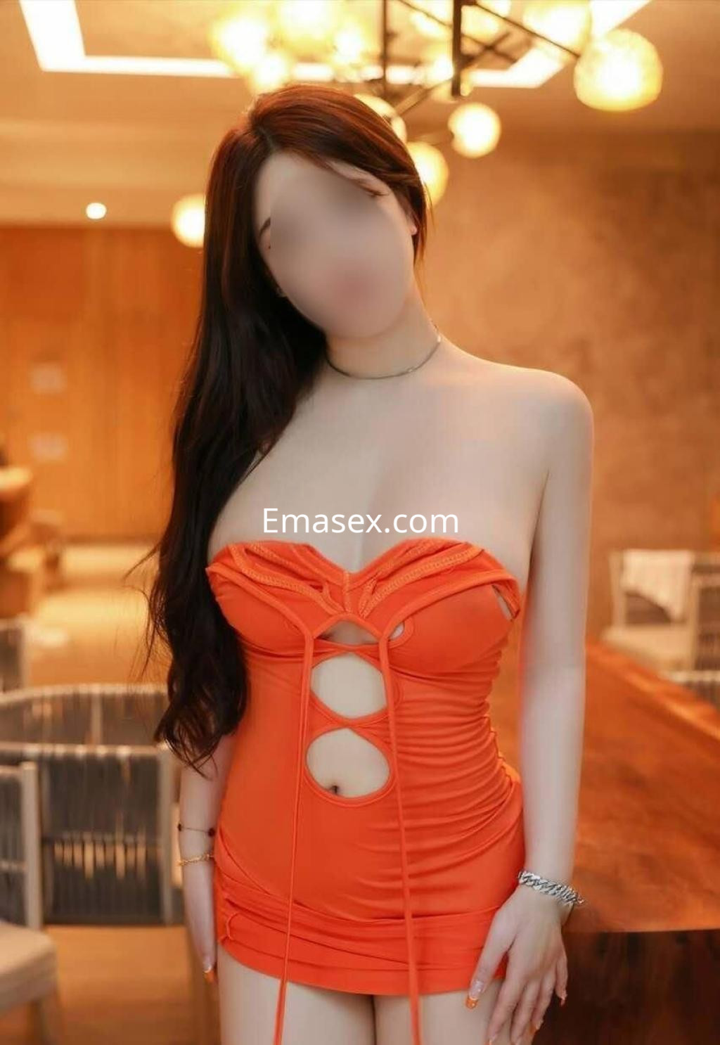Puta en Zaragoza luciendo un vestido corto naranja ajustado, con cabello largo y ondulado en un entorno moderno.