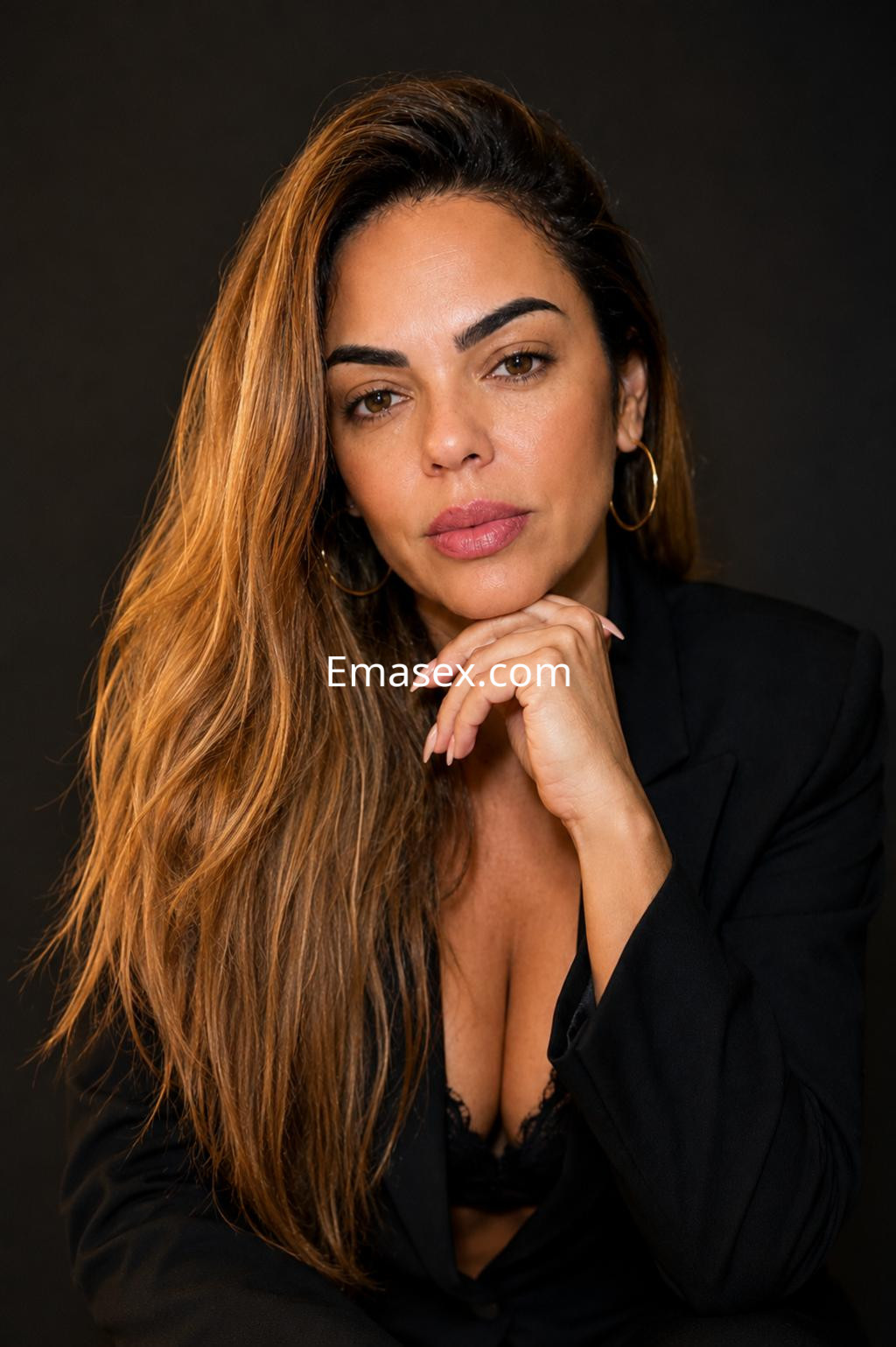 La puta en Donosti lleva un blazer negro y un sujetador de encaje, posando con una expresión seductora.