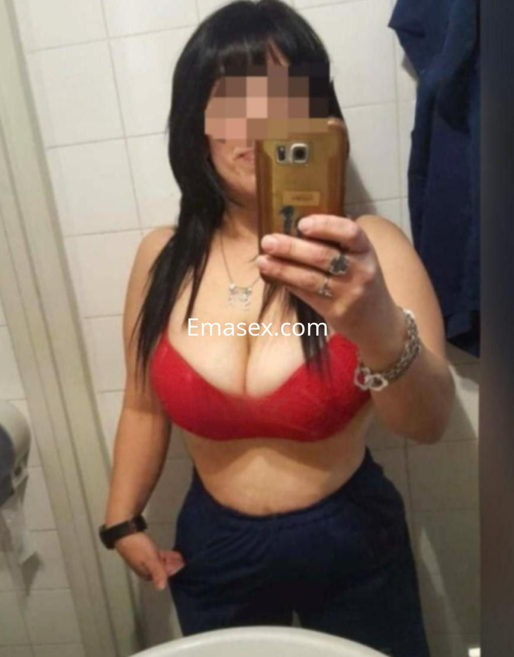 La escort en Madrid lleva un sujetador rojo y pantalones oscuros, posando frente a un espejo en un baño.