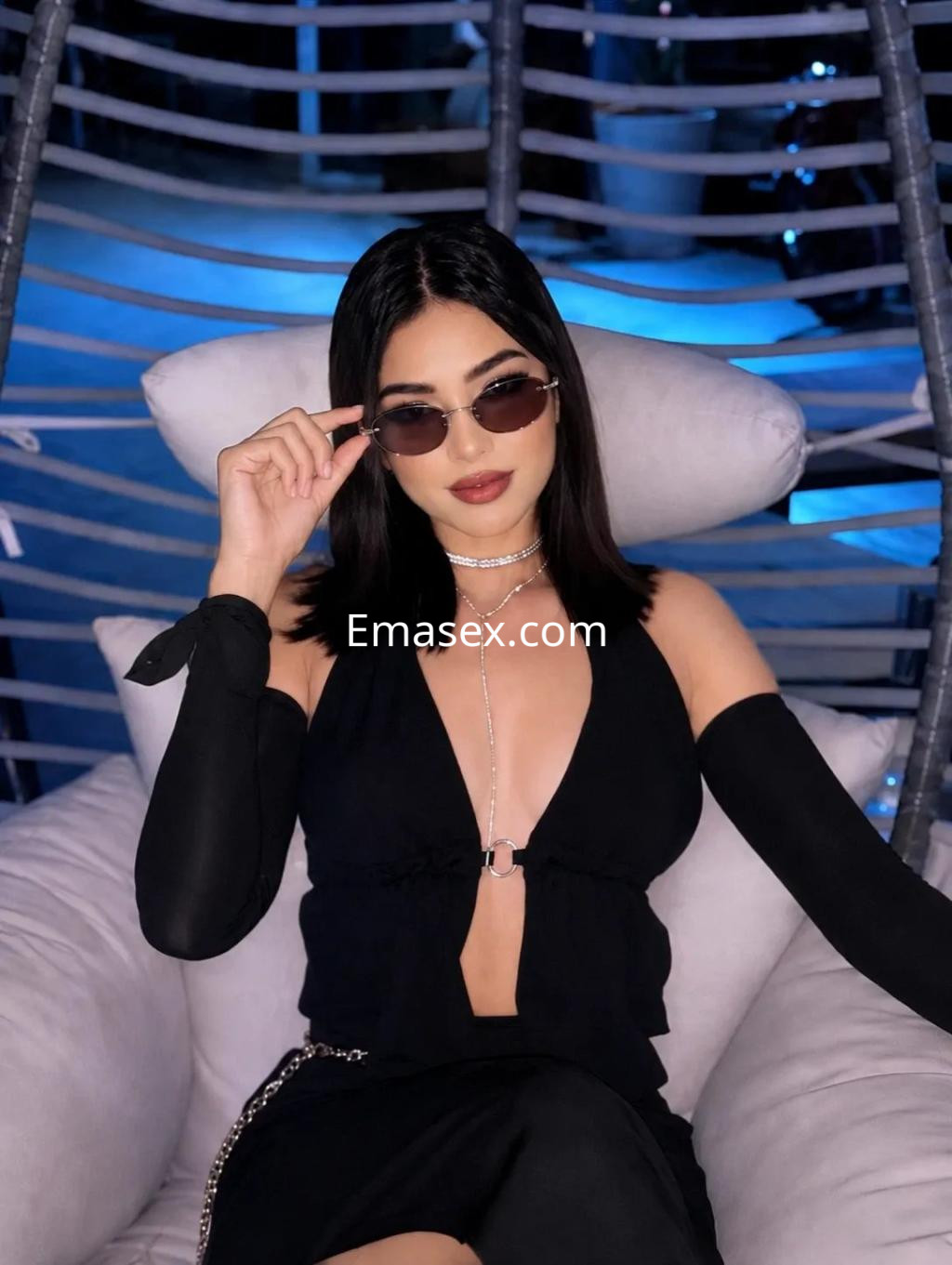 Puta sentada en un sillón, luciendo un conjunto negro con mangas largas y gafas de sol en Palma de Mallorca.