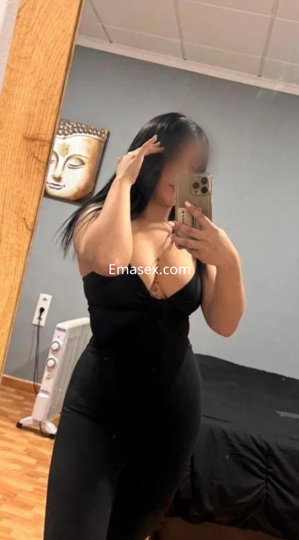 Puta en Castellón posando en un espejo, luciendo un vestido negro ajustado con escote profundo y cabello lacio.
