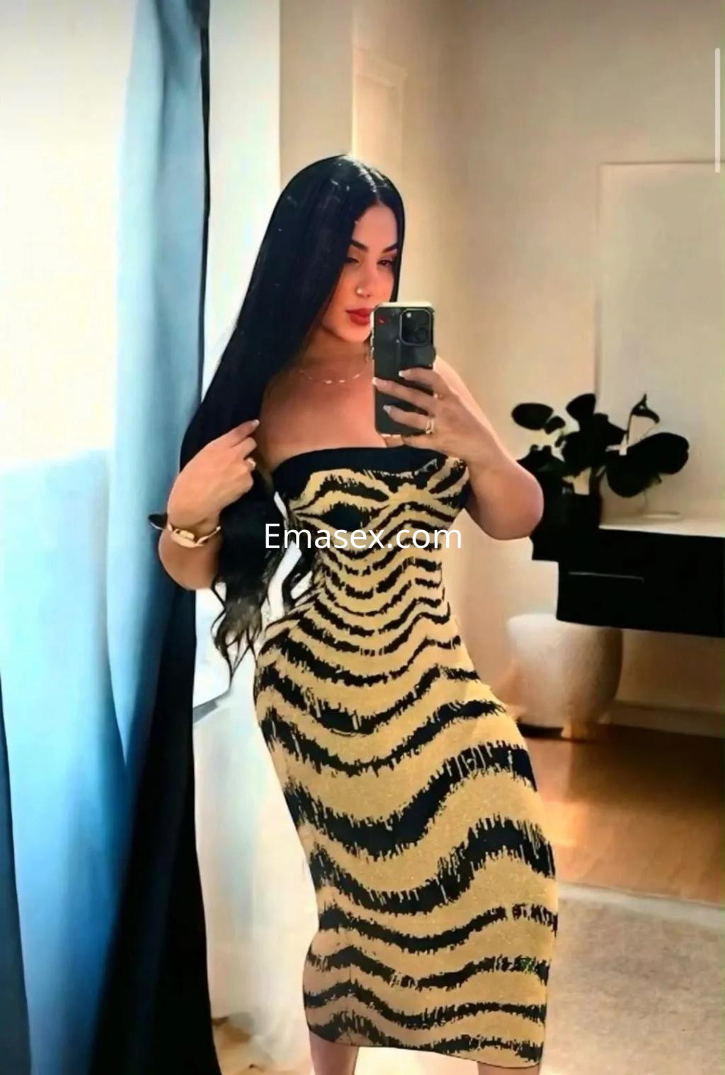 La puta viste un vestido ajustado de estampado de cebra en tonos dorados y negros, en un entorno de casa en Alicante.