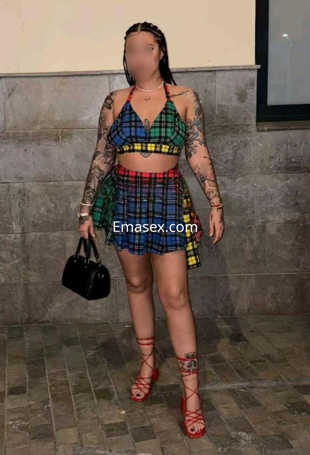 Puta en Santander con un conjunto de dos piezas a cuadros en tonos verde y azul, luciendo sandalias rojas.