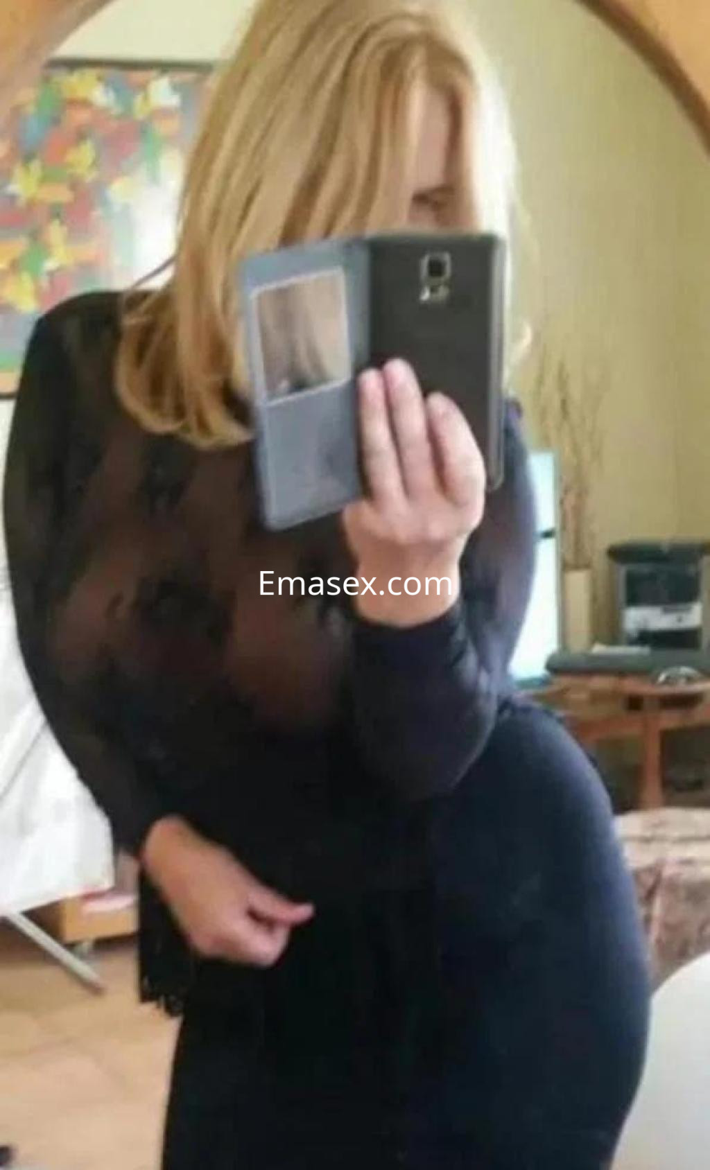 La puta en Ourense lleva una blusa negra transparente que resalta su figura y su cabello rubio.