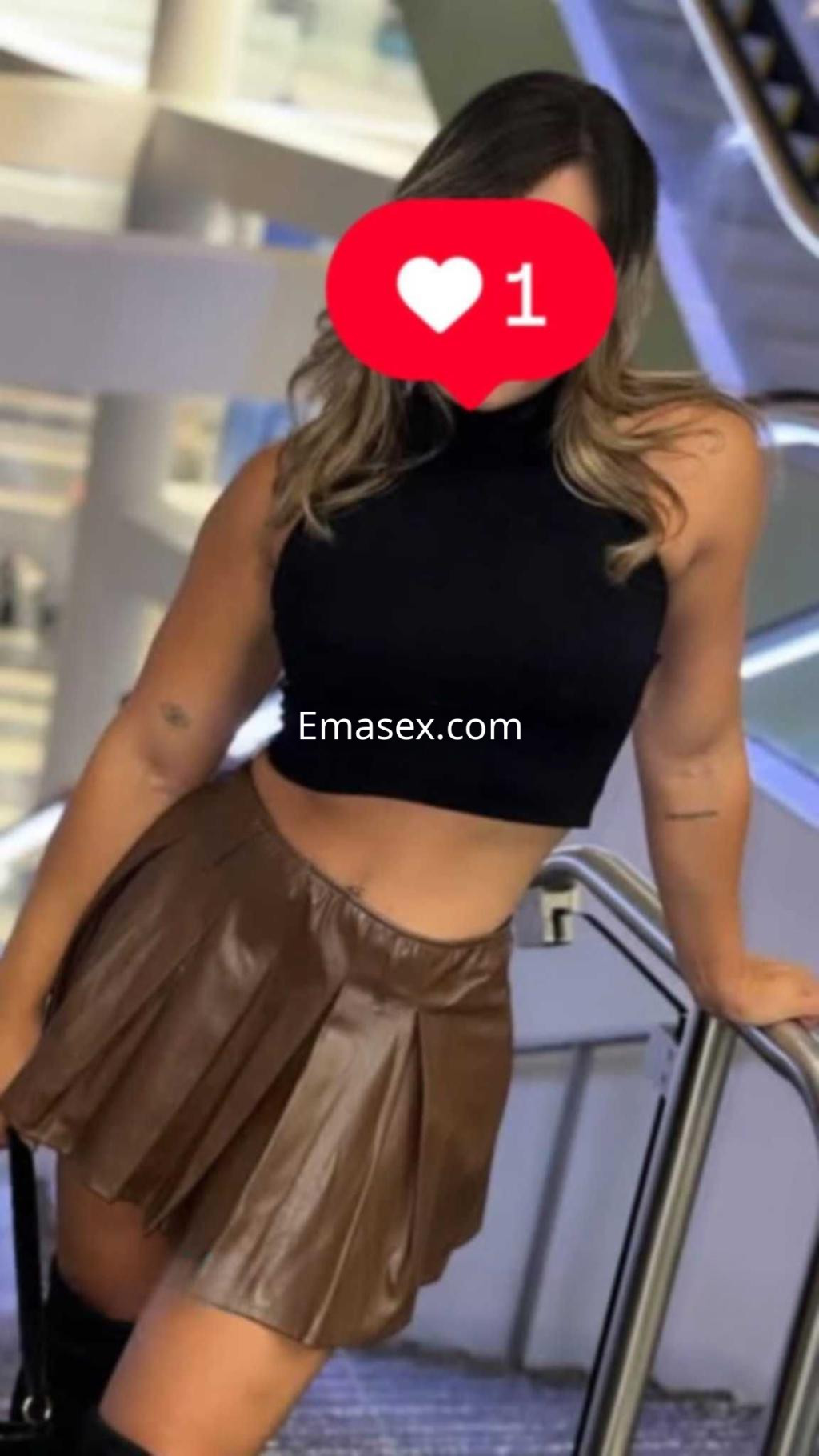 La puta viste un top negro y una falda corta de cuero marrón mientras posa en una escalera en Granada.