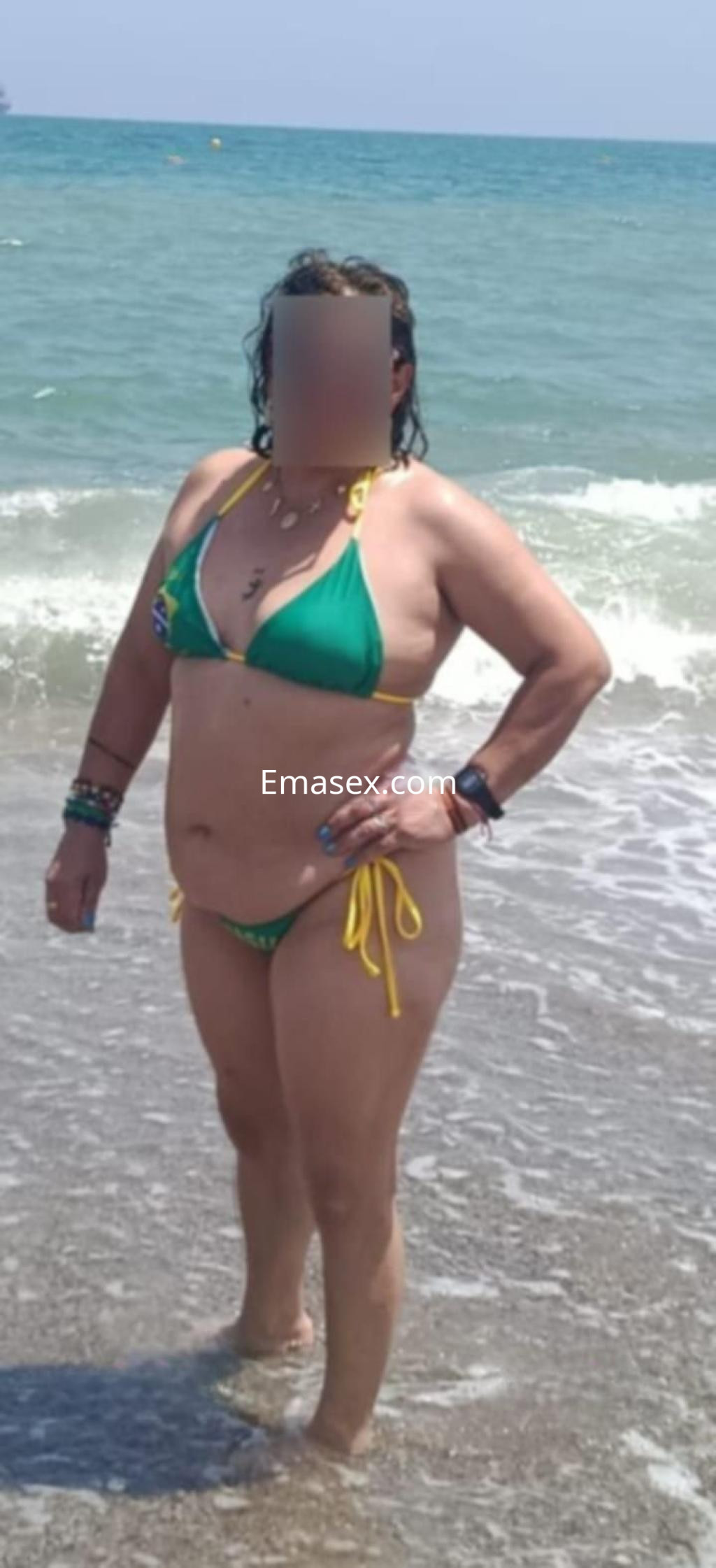 Puta en la playa de Granada, luciendo un bikini verde con detalles amarillos y disfrutando del mar.