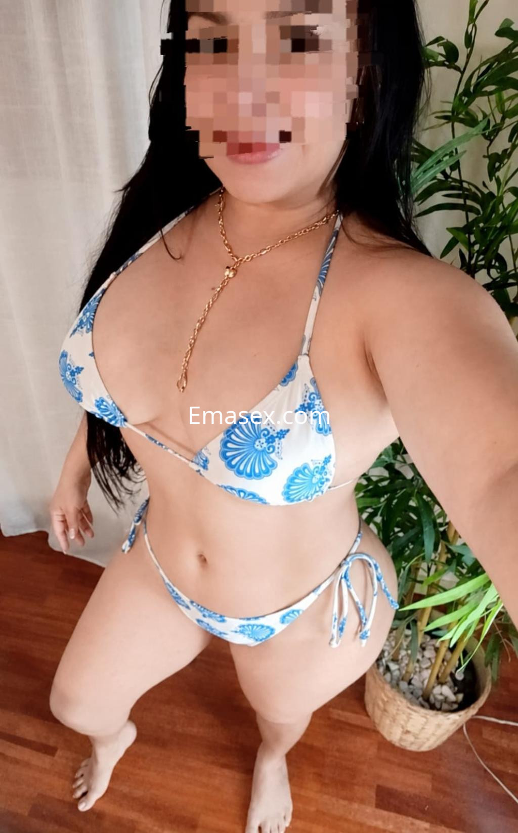 Puta en Pamplona, posando con un bikini blanco con estampado azul y una cadena dorada, sonriendo frente a la cámara.